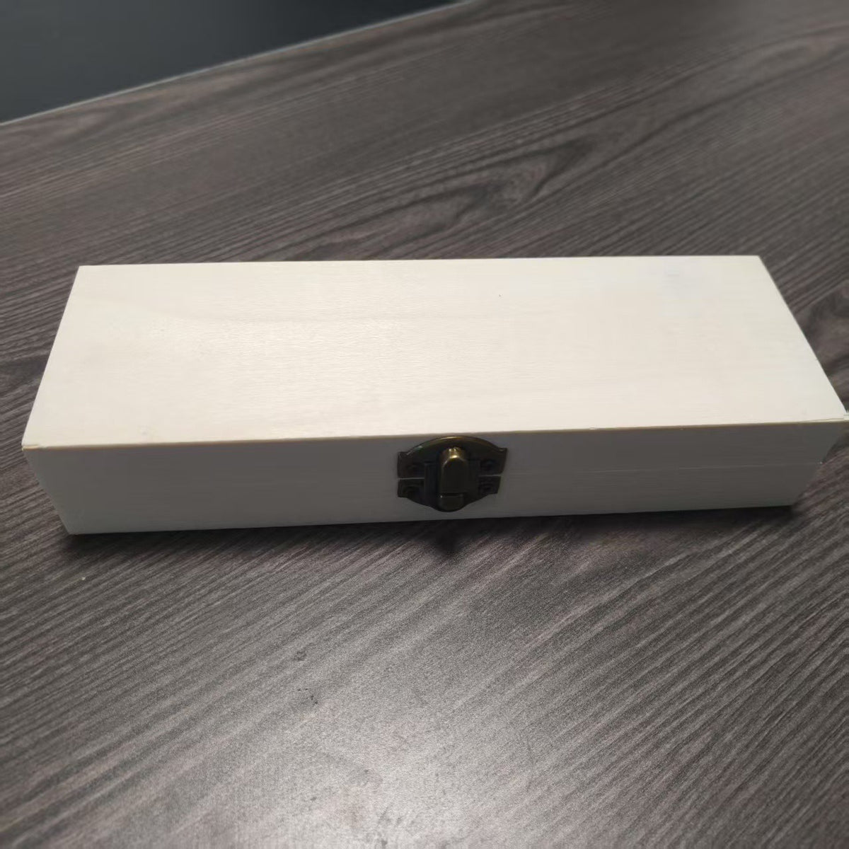 Die geschlossene cremefarbene Holzbox mit Metallverschluss