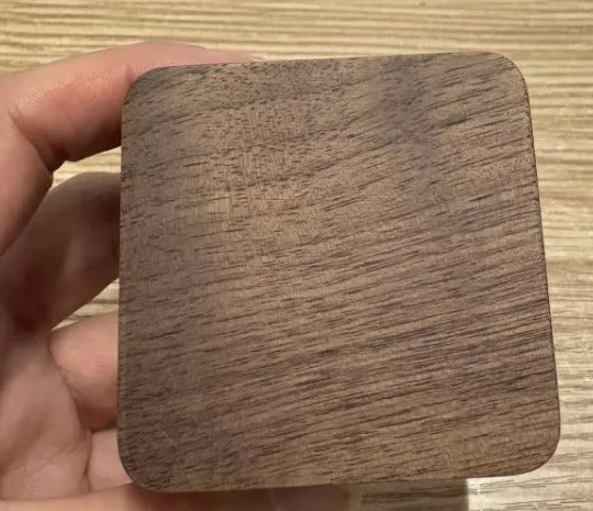 Geschlossene Ringbox aus dunklem Holz in einer Hand, glatter Deckel vor der Gravur